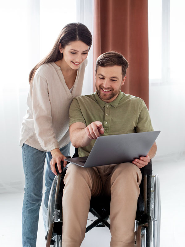 Aus Care Community Services | Local NDIS Providers | Home Man using a wheelchair looking at a laptop with a support worker