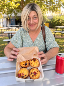 Aus Care Community Services | Local NDIS Providers | Home Jacinta, an Aus Care Community Services participant, smiling with a box of Portuguese tarts, her favourite dessert, from a Portuguese festival in her community.